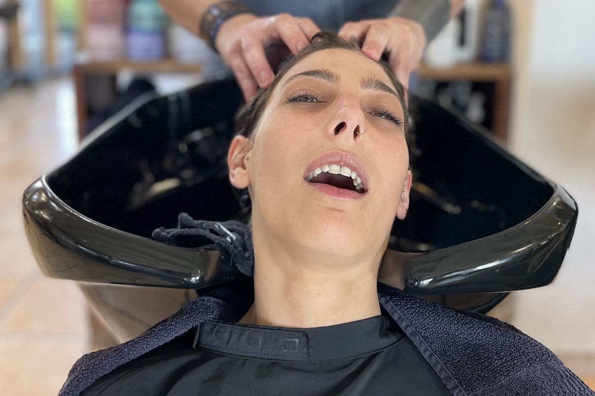 Une femme en train de profiter d'un shampooing au salon de coiffure Aurelien Magnano